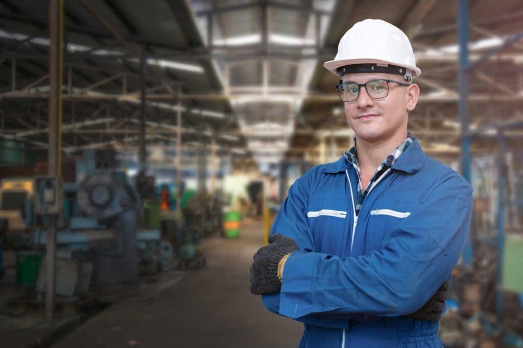 Portrait of manual man worker is standing with confident with blue working suite dress and safety helmet in front machine and equipment for heavy industry factory.